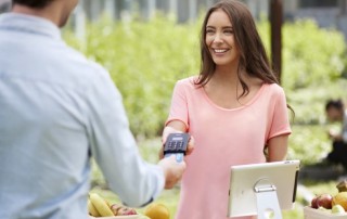 positive woman accepting card reader payment from man
