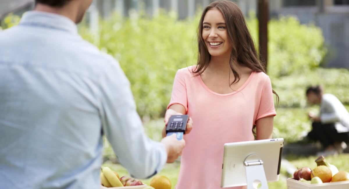positive woman accepting card reader payment from man