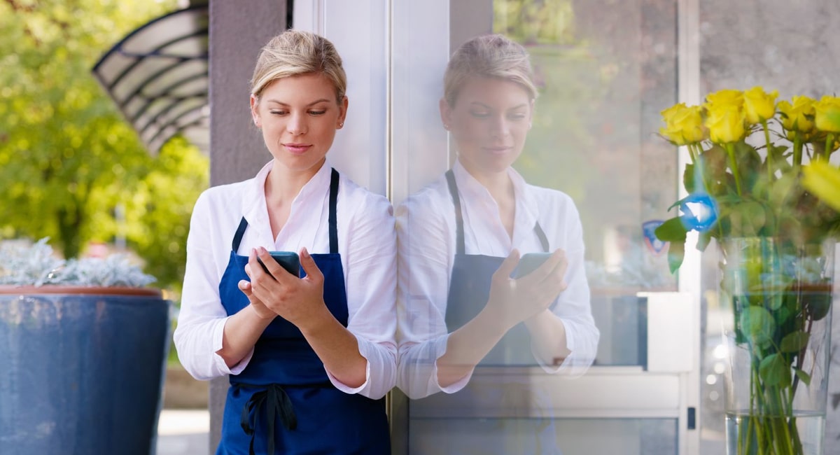 waitress looking at her phone outside a restaurant