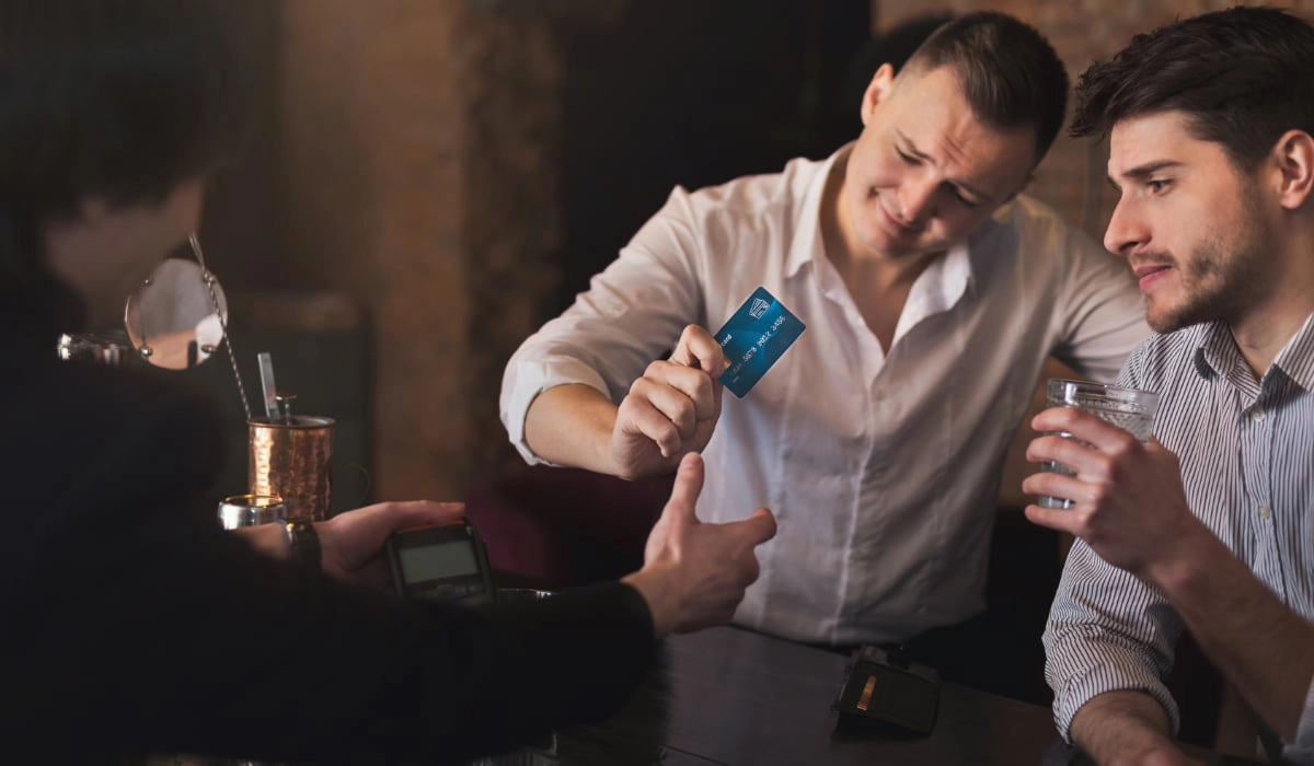 two men paying with card in a bar