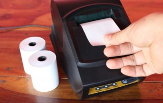 Receipt printer with paper rolls and hand ripping off receipt