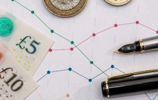 Pound notes and coins with sales figures and pens