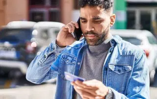 man on his phone while holding credit card