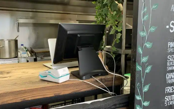 Restaurant POS register with a payment terminal next to menu board
