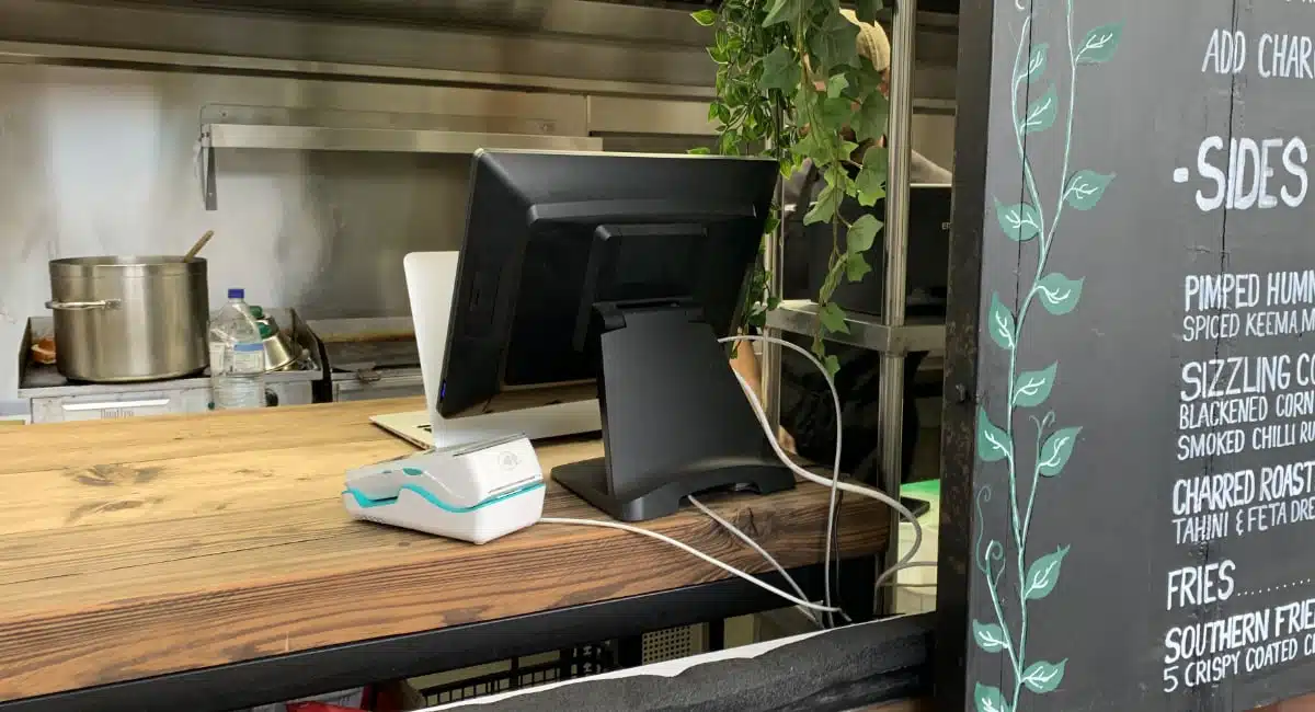 Restaurant POS register with a payment terminal next to menu board