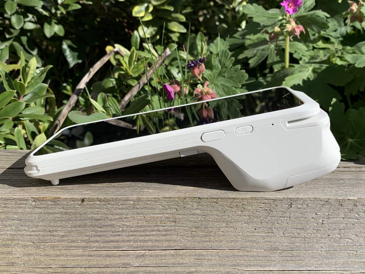 SumUp Terminal looks good in the sun SumUp Terminal's right side when lying on a wooden surface with bushes behind
